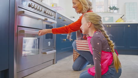 Abuela-Y-Nieta-Sacan-Pastelitos-Recién-Horneados-Del-Horno-En-La-Cocina-De-Casa