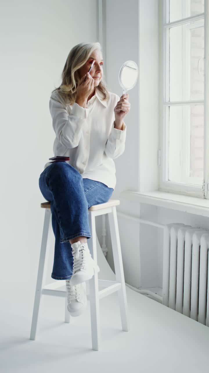 Woman applying makeup while sitting on a stool