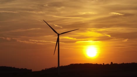 vista aerea di una turbina eolica in silhouette contro un tramonto dorato