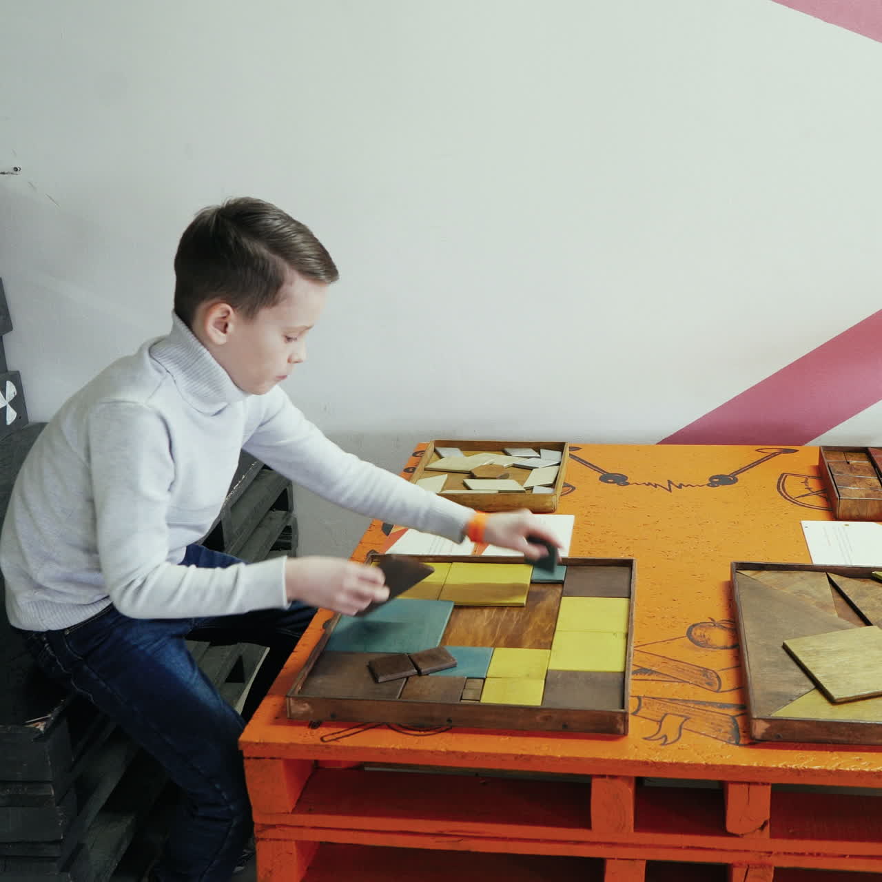 Boy playing with a puzzle of wood. Kid in the scientific center. Square video