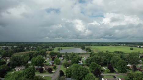 an aerial shot of a road in cloudy weather near a field with green wheat and a delta with flowering rapeseed