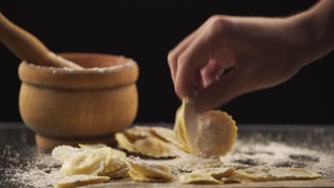 tasty raw ravioli with flour and basil on wood table