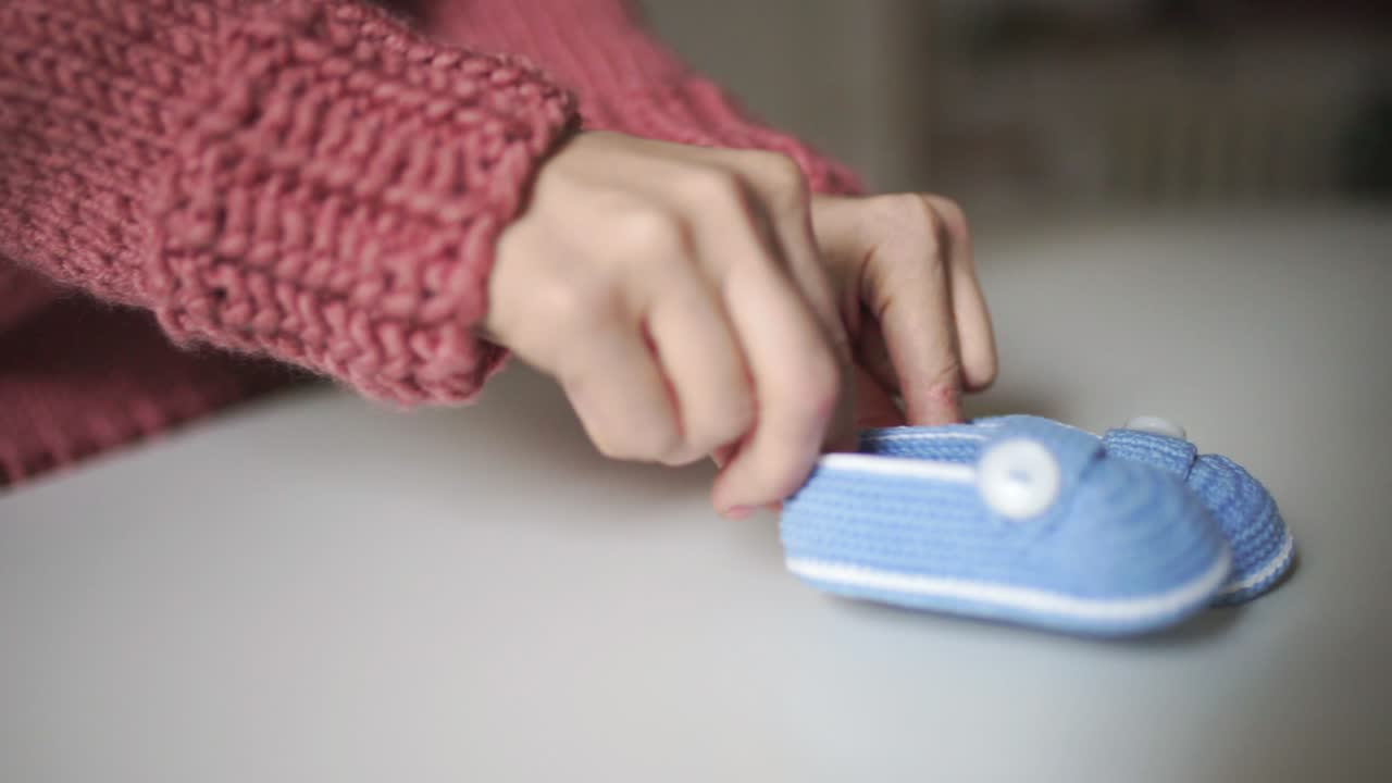 manos femeninas jugando con botines de punto para bebés. zapatos de punto hechos a mano para bebés