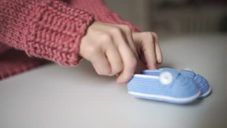 Manos-Femeninas-Jugando-Con-Patucos-De-Punto.-Zapatos-De-Punto-Hechos-A-Mano-Para-Bebé