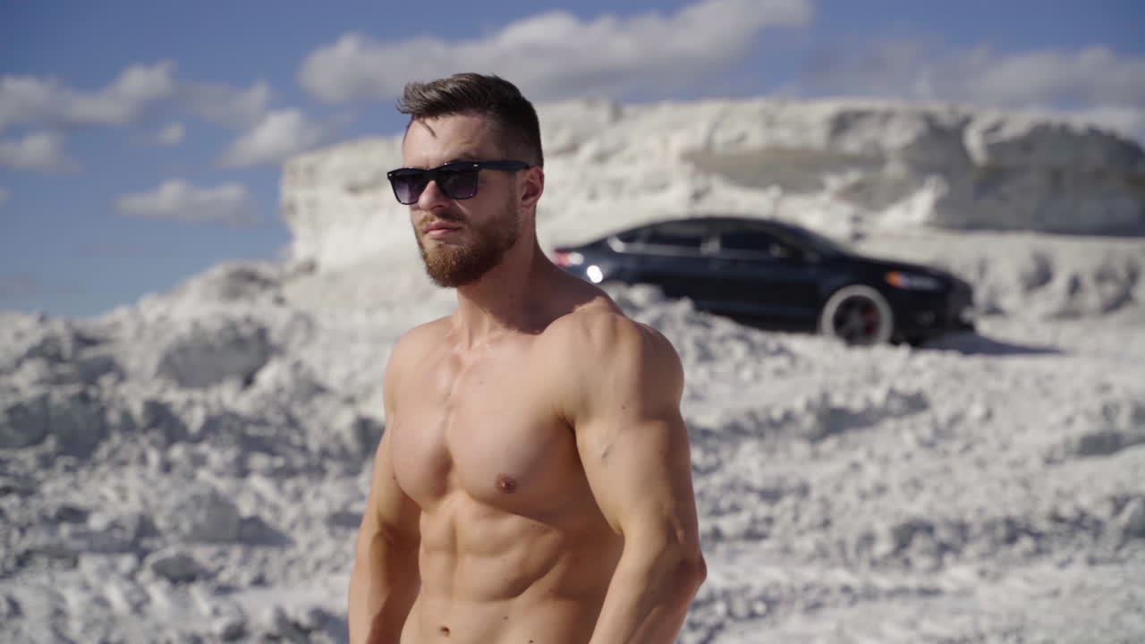 Bodybuilder posing on nature. Beautiful and muscular young shirtless man