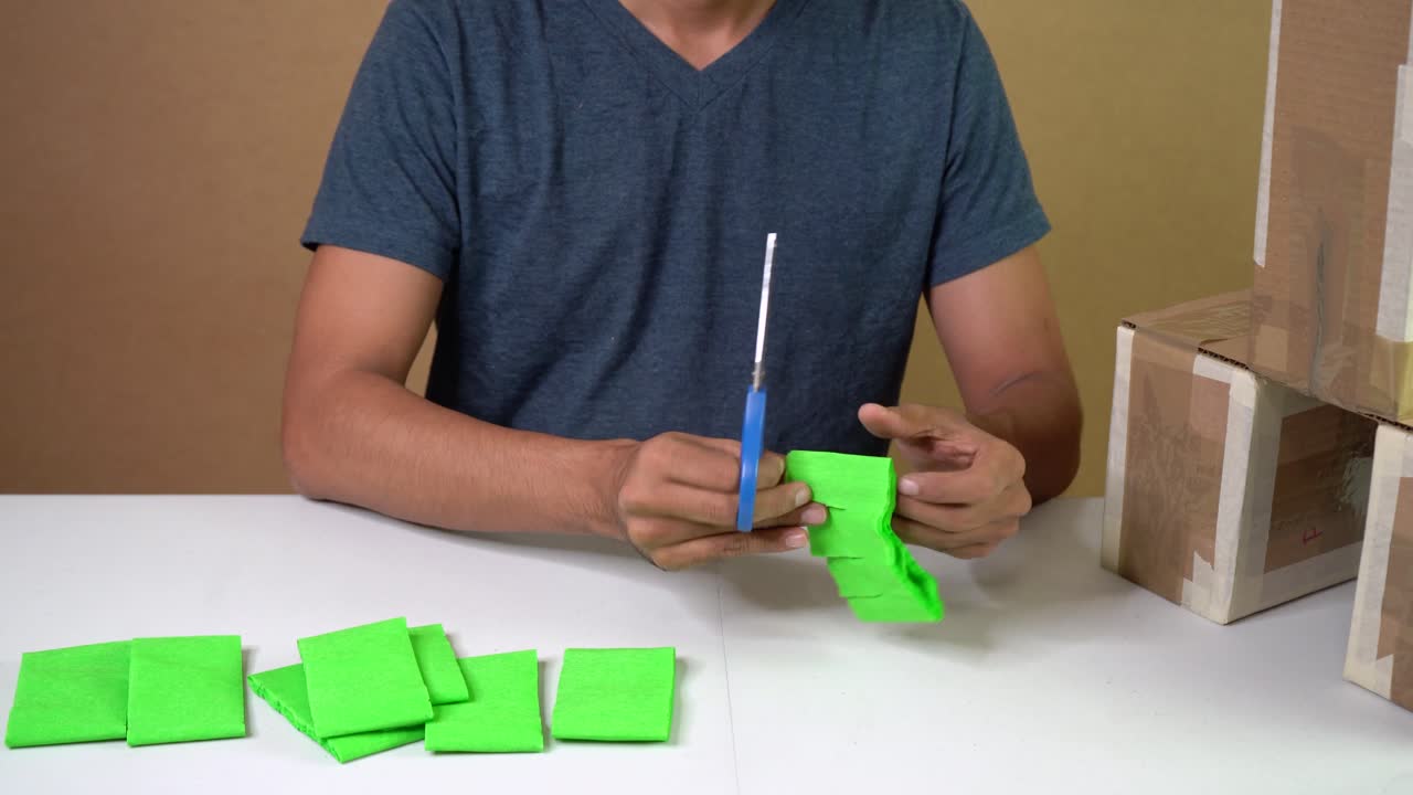 Man cutting green crepe paper with scissors, arts and crafts