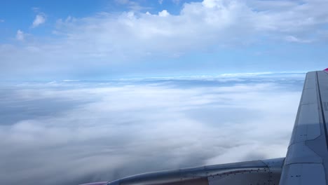 view of airplane wing above clouds during a sunny flight