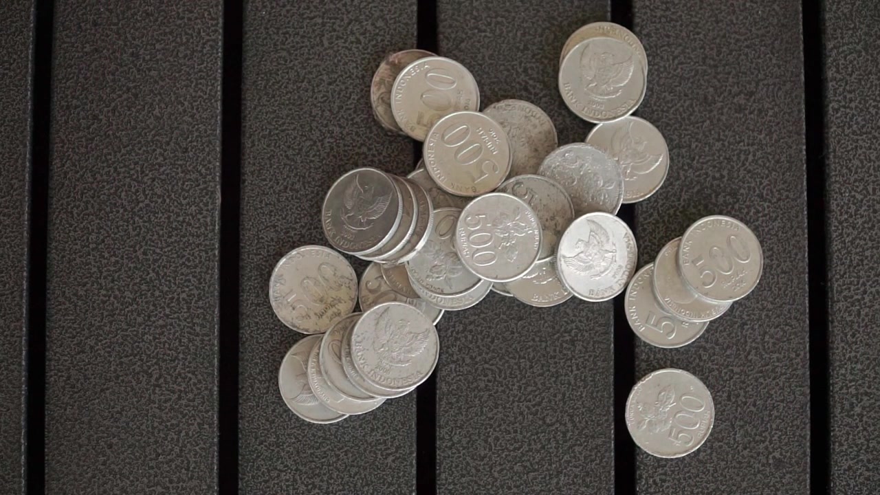 The hand pushing a collection of coins, symbolizes payment, depositing wealth, personal finance, economics, budgeting, and the concept of handling cash.