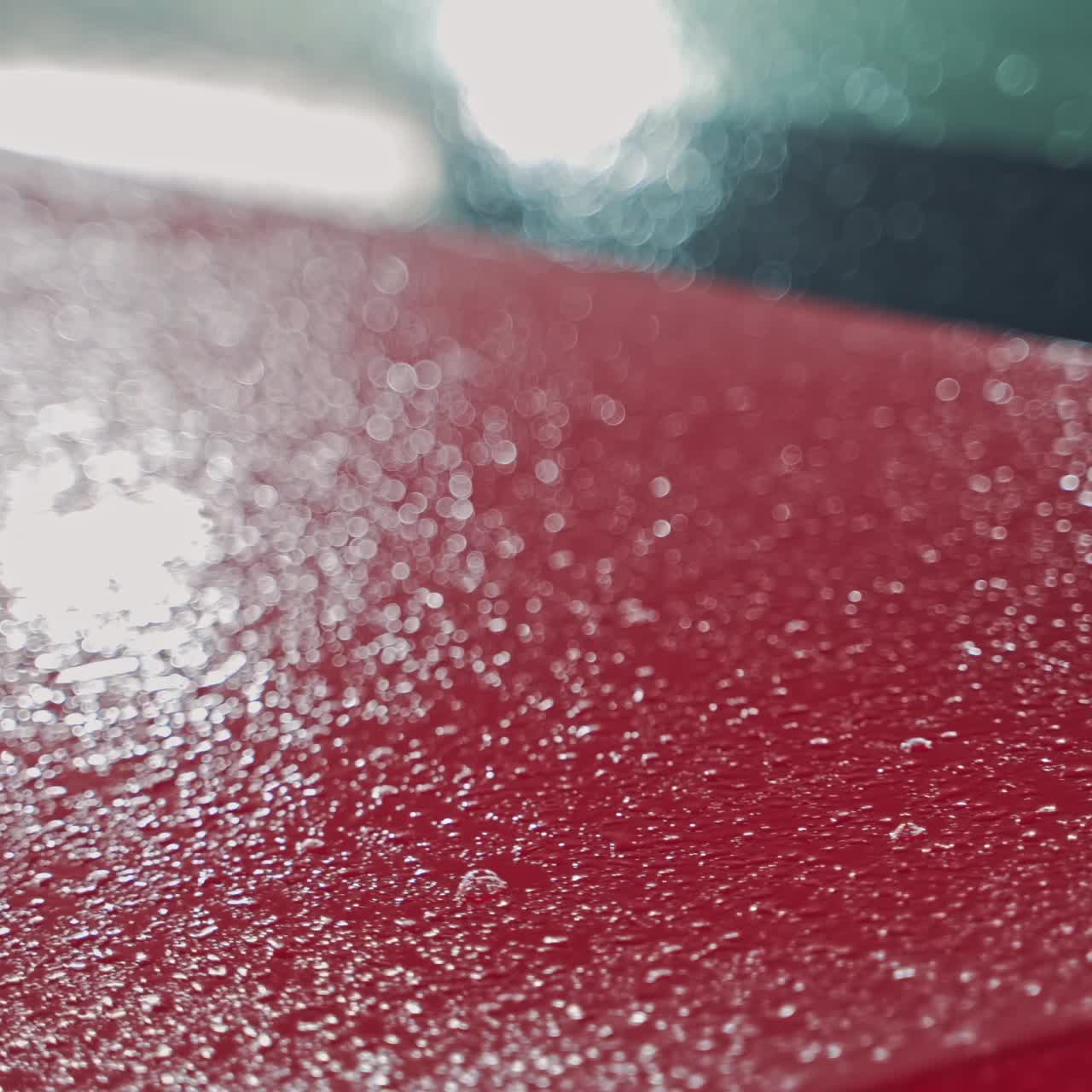 Washer cleaning red car at service station