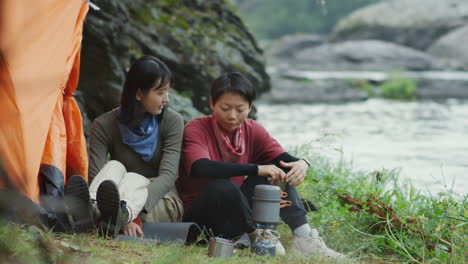 lesbian couple cooking food at campsite
