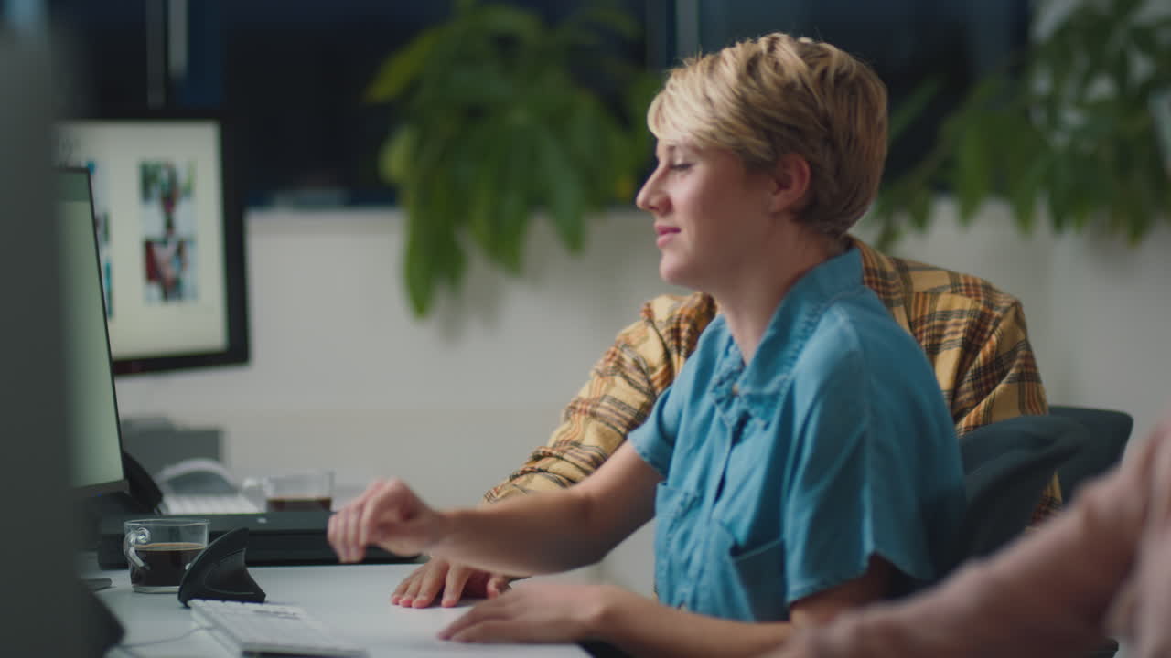 Two Business Colleagues At Desks In Office Working Late On Project Together