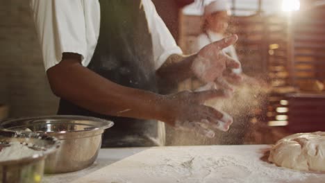 animation of midsectin of african american male baker clapping hands to clean flour