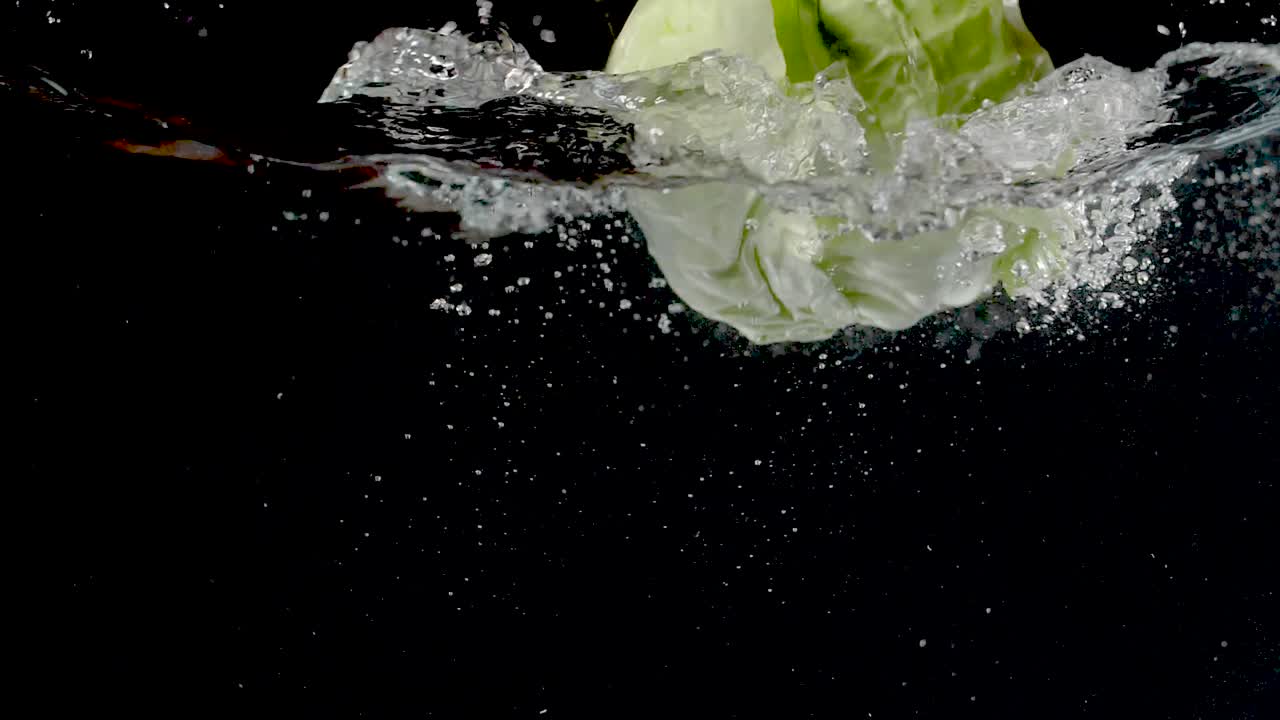 repollo colorido que se deja caer en el agua en cámara lenta