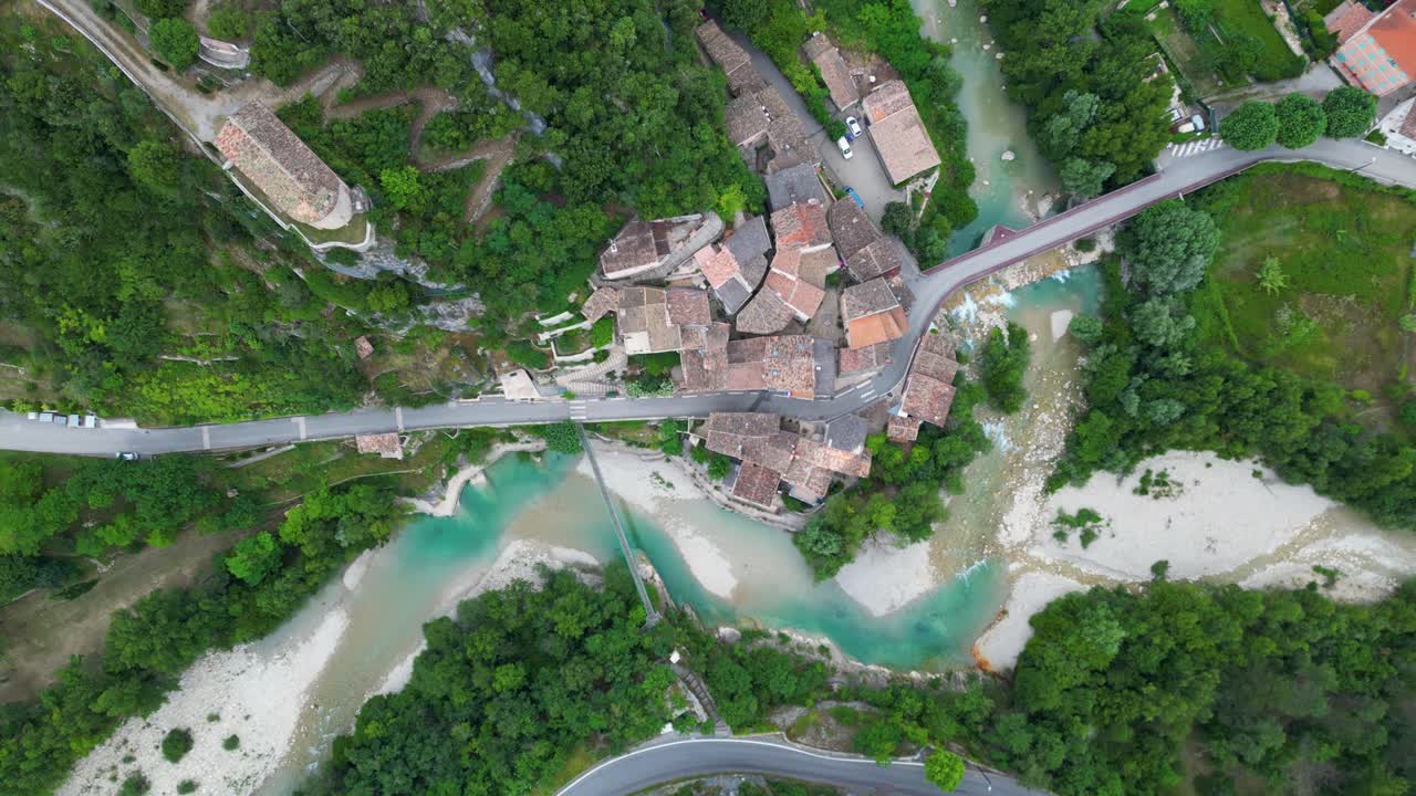 Overhead drone shot capturing the peacefulness of a French village surrounded by rolling mountains.