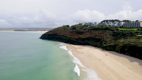 People-walking-along-St-Ives-beach-with-panoramic-view-of-promontory,-Cornwall