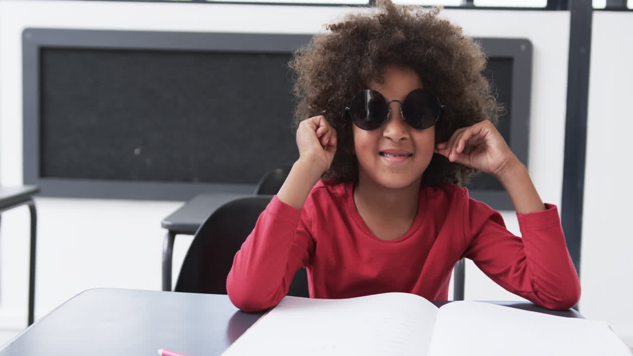 Em uma sala de aula escolar, uma criança afro-americana senta-se em uma carteira