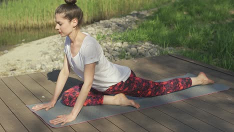 mujer joven haciendo ejercicios de yoga en la alfombra en el día de verano