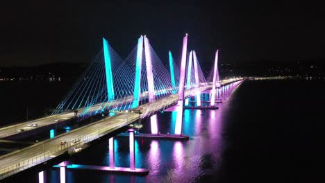 an aerial view of the mario cuomo bridge in new york, illuminated at night, taken by a drone camera.