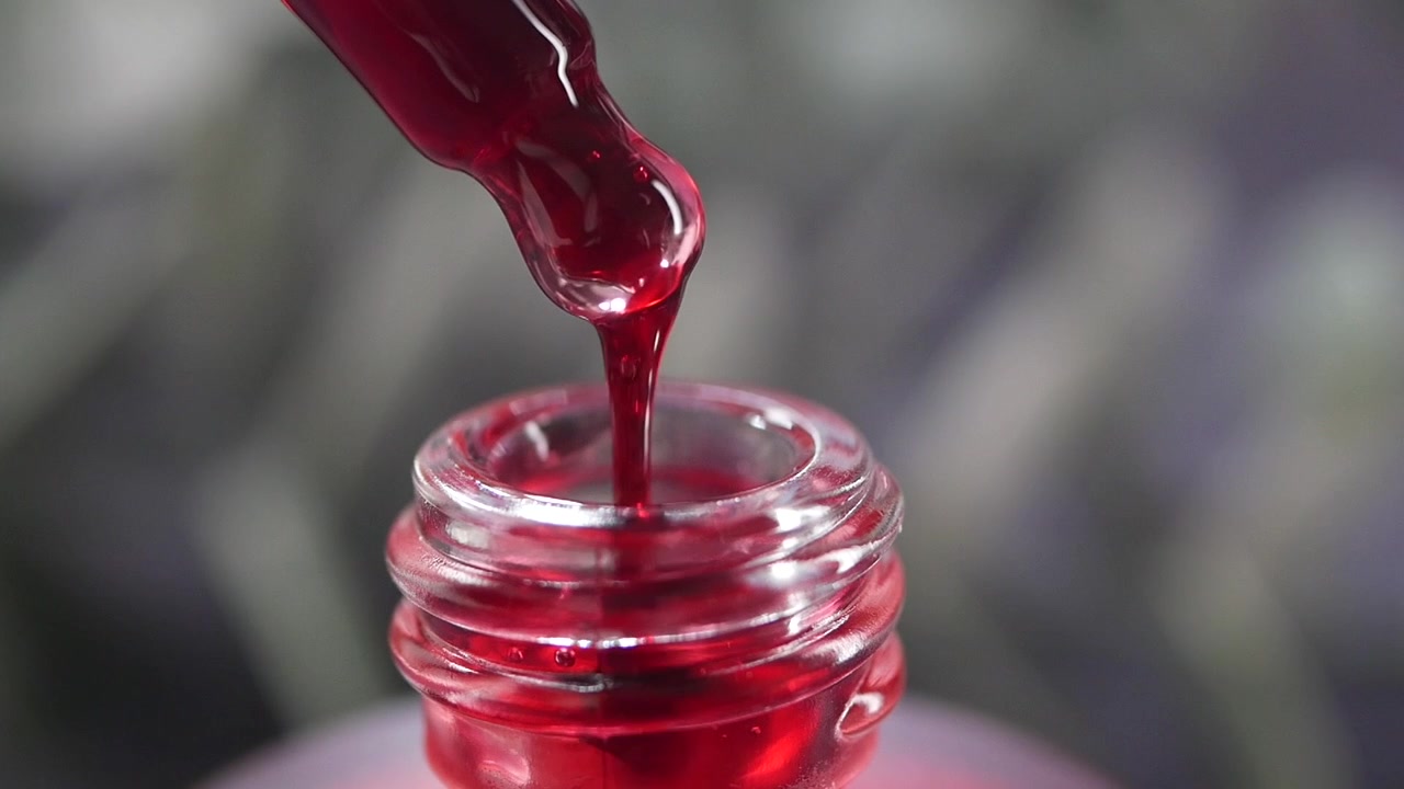 Red Liquid Dropping from Glass Pipette into Bottle