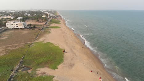 ecr chennai beach full of people surrounded by trees, construction, and buildings top view during sunset