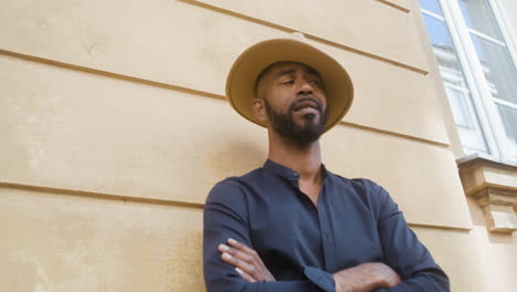 afro caribbean man with panama hat and crossed arms standing in the old town street and looking around