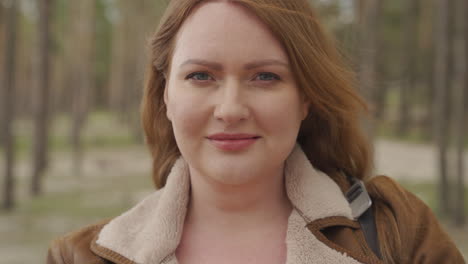 portrait of a beautiful smiling red haired woman in the forest