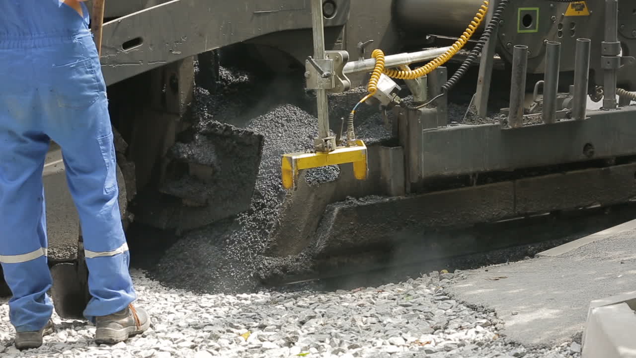 Tracked pavers laying fresh asphalt pavement on a street