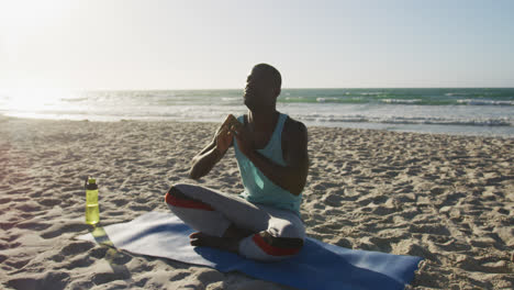 Hombre-Afroamericano-Enfocado-Practicando-Yoga-En-La-Playa,-Haciendo-Ejercicio-Al-Aire-Libre-Junto-Al-Mar