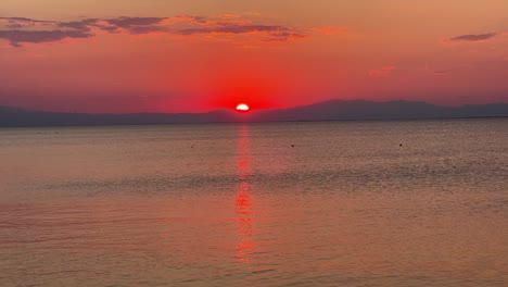 Hermosa-Puesta-De-Sol-Roja-Dorada-Sobre-La-Montaña-Con-Un-Sendero-Solar-Sobre-El-Mar