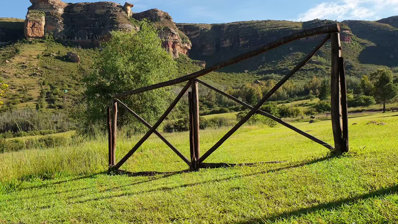 Camelroc guest farm wooden fence and green grass slowly moving up over fence to show the sandstone cliff mountains