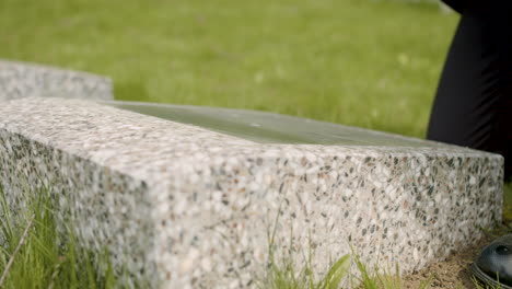 vista de cerca de un hombre irreconocible con traje negro limpiando una lápida con un pañuelo en un cementerio 1