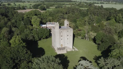 a medieval norman keep enclosed by deep green forest on a warm summery day