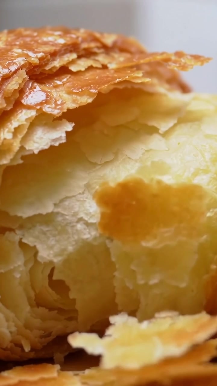 Video verticale: Sollevando la crosta, un croissant rivela gli strati sul bancone, con scaglie per l'ispezione.