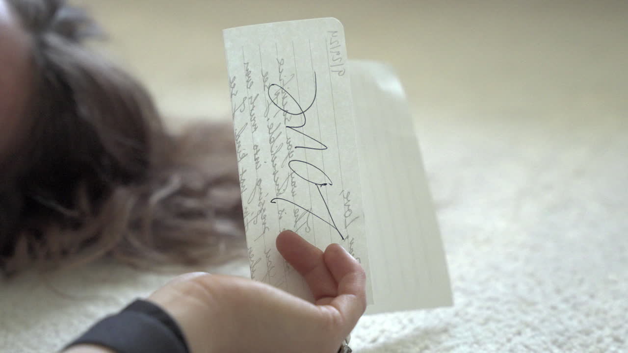 A close-up shot of a woman's hand gently holding a handwritten love letter. The camera slowly moves, highlighting the delicate details of the letter and her emotions.