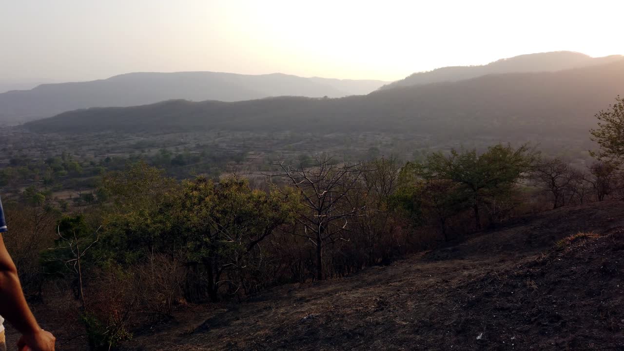Young Man Standing and Seeing the Sunset Across the Mountains and a Valley with Beautiful Scenery