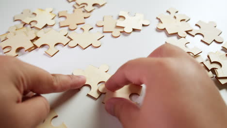 A-person-trying-to-solve-a-Jigsaw-Puzzle-without-pictures,-left-hand-holding-the-pieces-in-place-while-the-right-hand-adds-one-piece-after-another