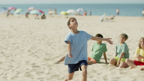 long shot of boy running on beach and kicking ball with leg