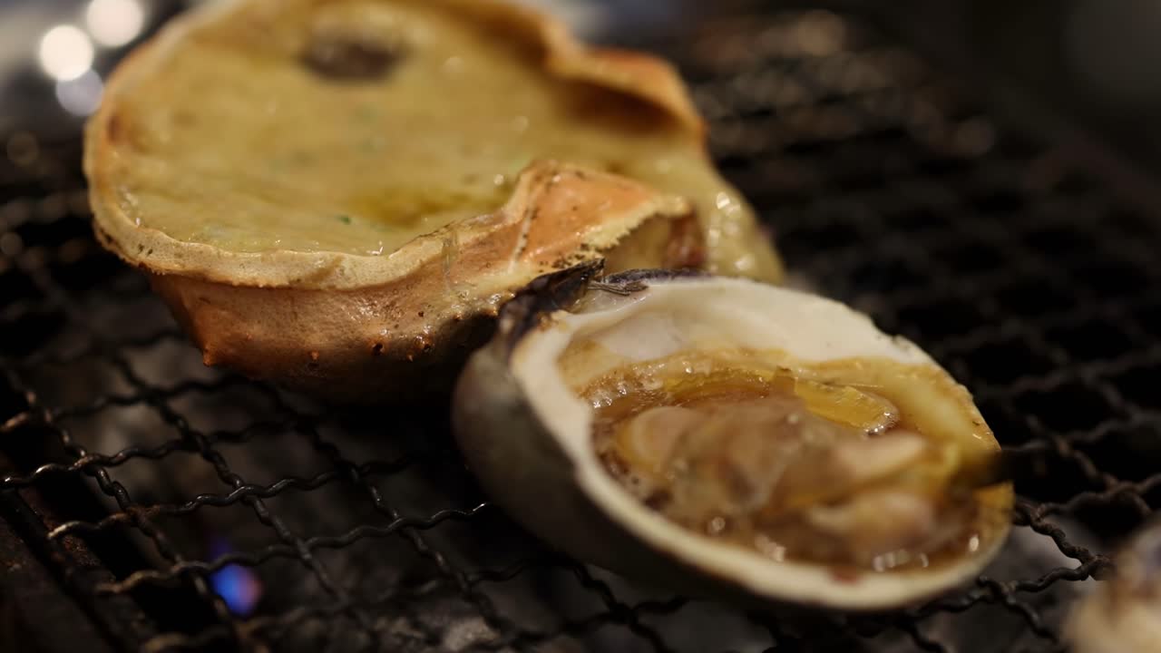 Close-up of shellfish and cheese-topped shells grilling over an open flame, showcasing a savory culinary process.