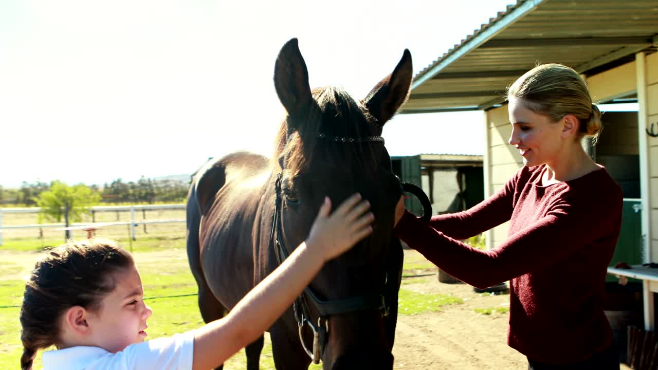 madre e hija acariciando caballo en el rancho 4k