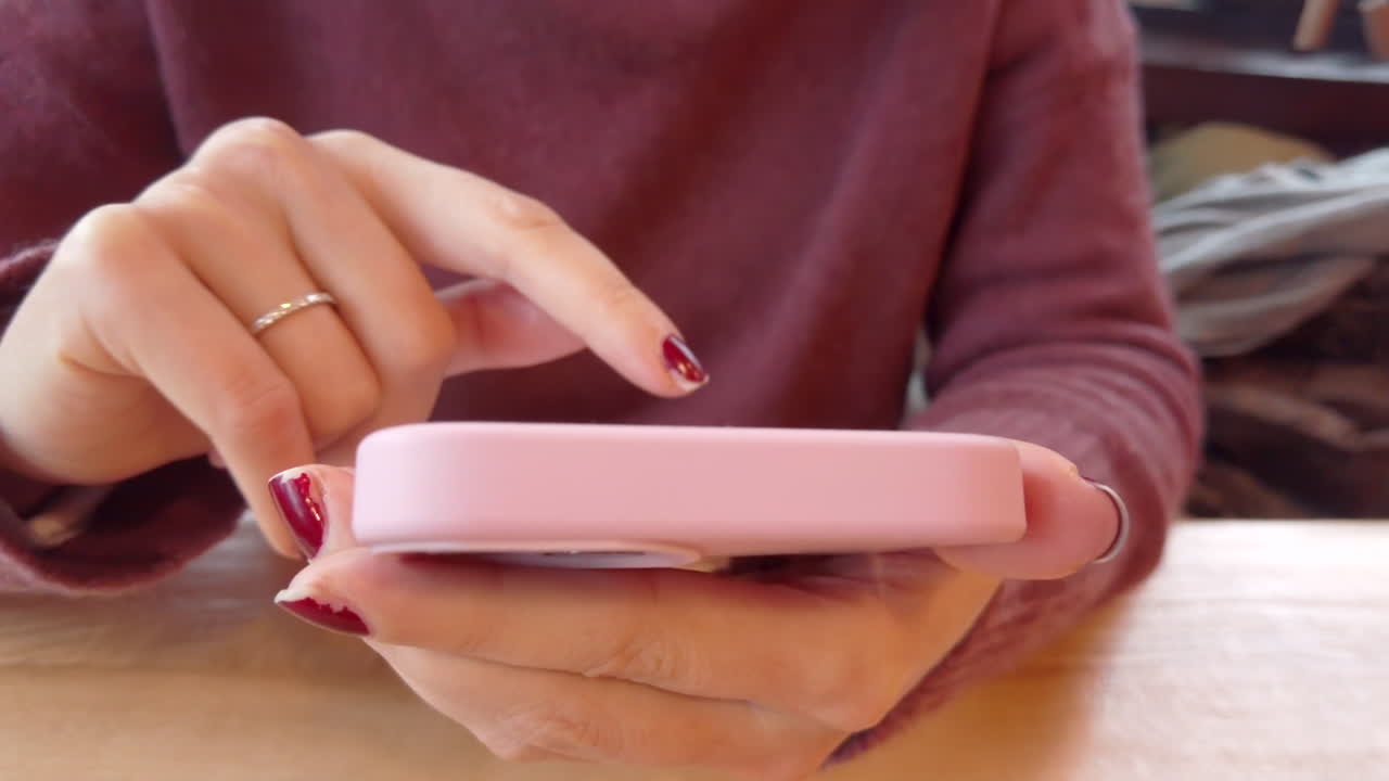 Woman scrolling through pictures on her phone at a cafe