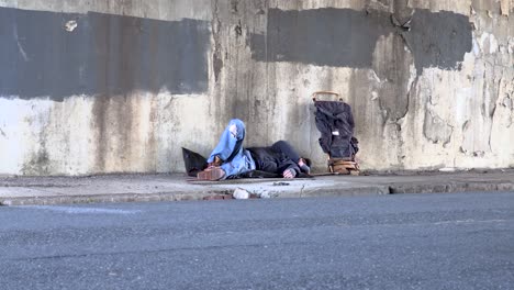 Toma-Amplia-De-Un-Varón-Adulto-Joven-Sin-Hogar-Desmayado-En-La-Acera-De-Un-Paso-Elevado