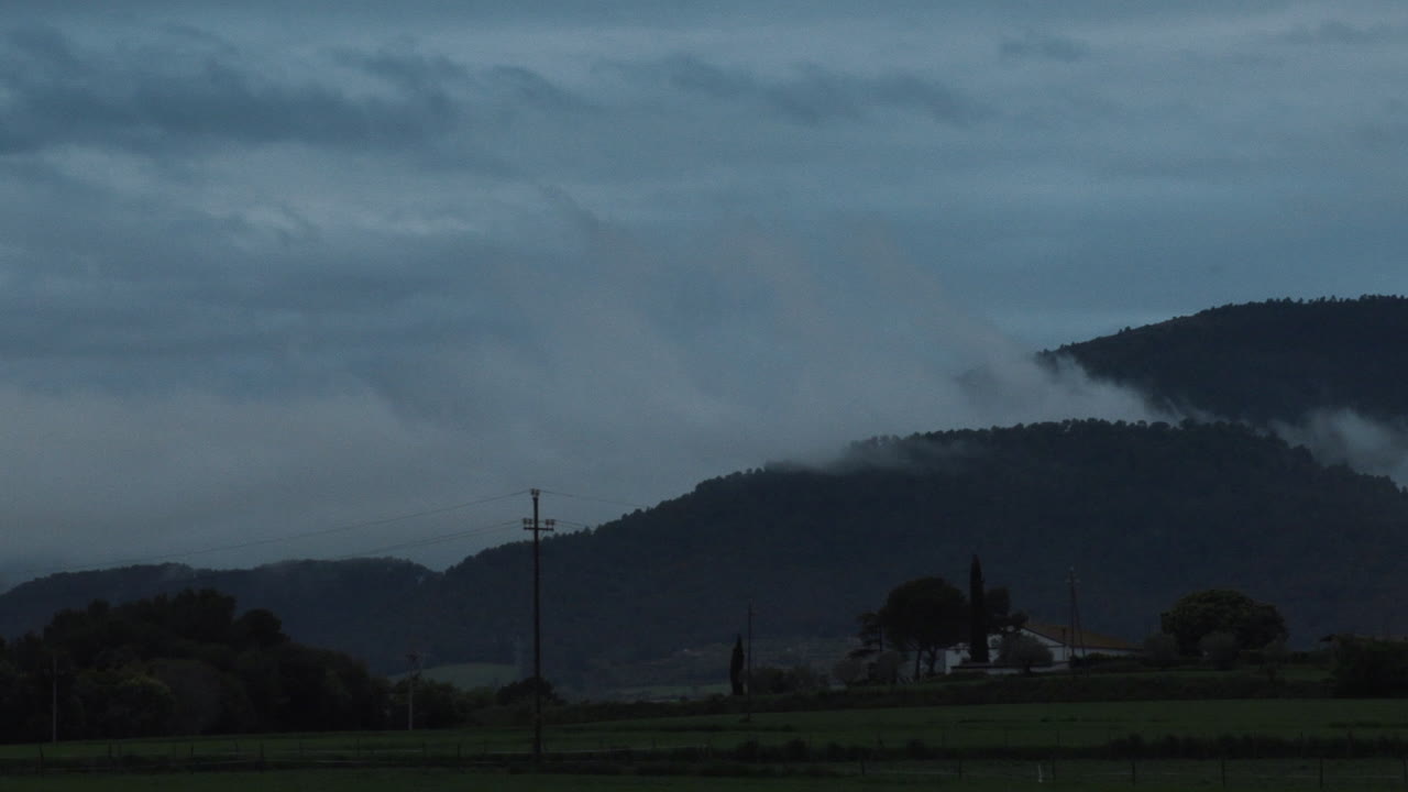 Timelapse zoom in of the movement of the clouds after a storm in a small Catalan town, the shot ends when night falls
