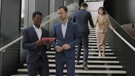 two male managers going downstairs while using tablet