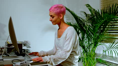 mujer de cabello rosa trabajando en una computadora 4k