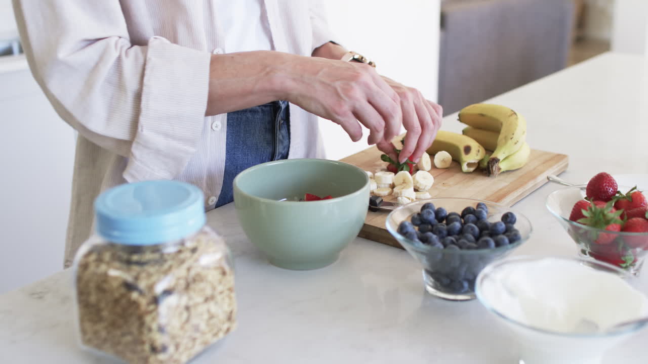 una mujer caucásica de mediana edad está preparando una ensalada de frutas