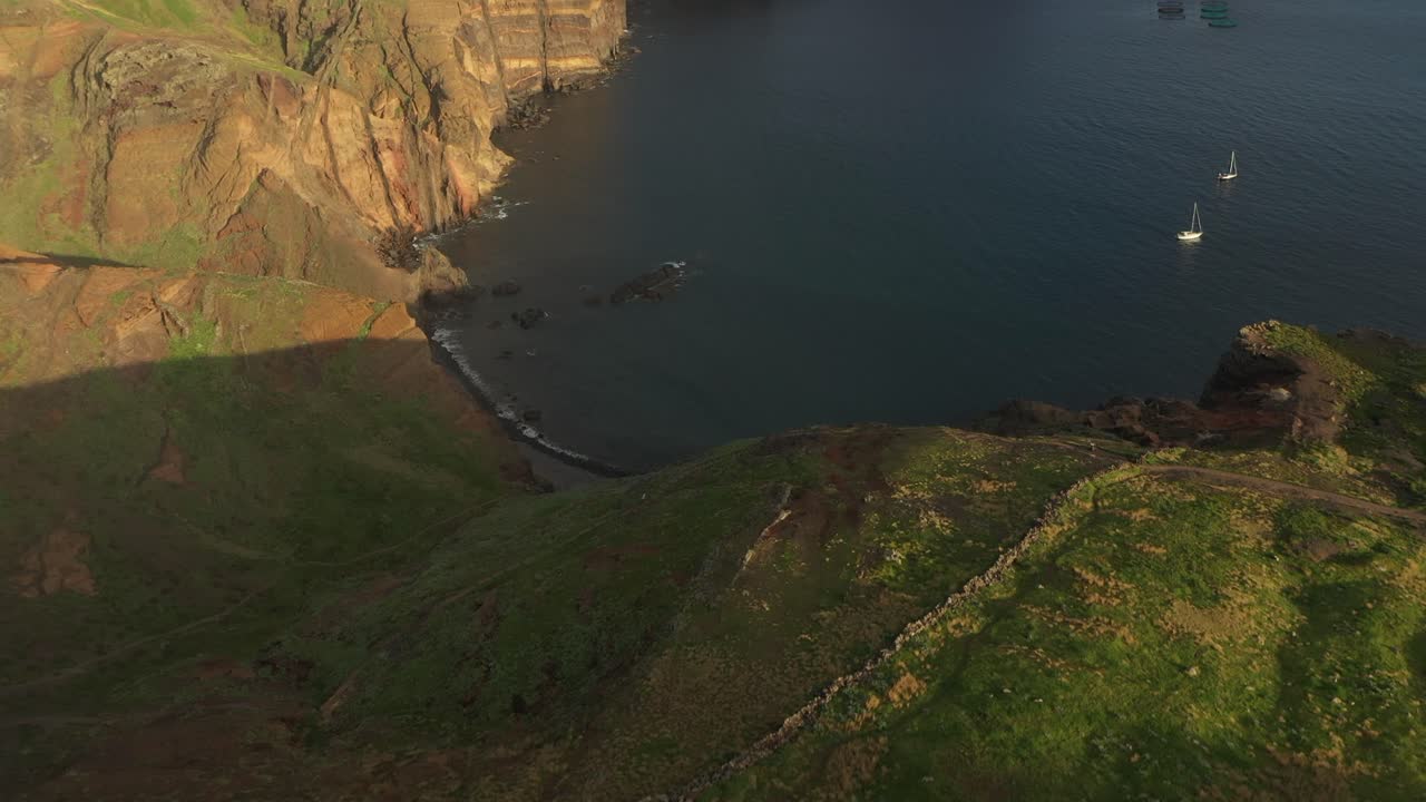 마데이라 해안에 있는 바다에 두 척의 흰색 보트가 있는 작은 만 위로 드론이 발사되었습니다.
