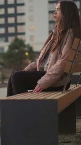 a girl in a peach jacket and black trousers is seen rollerblading towards a park bench. the image captures the moment before she sits down to rest, with her rollerblades visible on the paved path