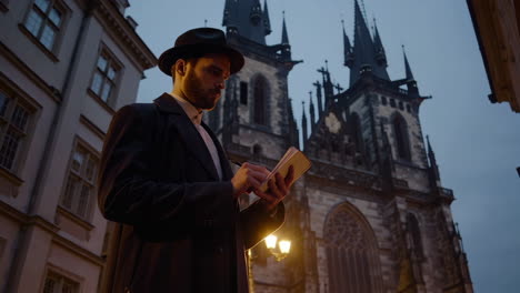 man writing in a notebook in prague at night