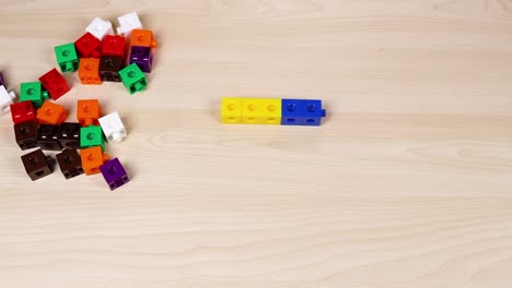 hand moves cubes on a wooden surface