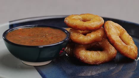 fried crispy onion rings dipping in red salsa ketchup sauce close-up macro. roasted onion rings for snacks at bar, cafe. fast food. delivery. beer snacks